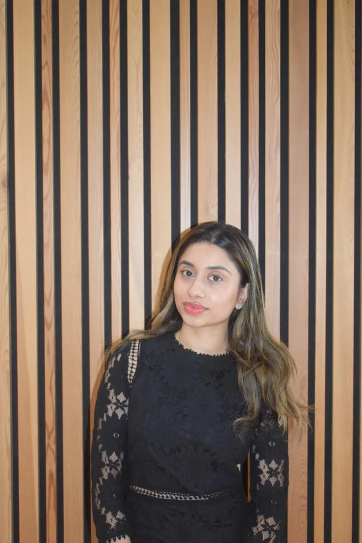 Portrait of Bhavisha Valgi in front of a wooden slatted wall.